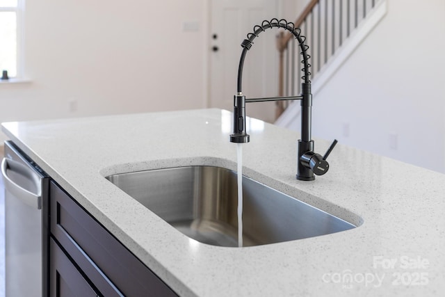 kitchen view of a sink, light stone countertops, and dishwasher