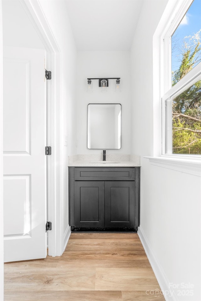 bathroom with wood finished floors, vanity, and baseboards