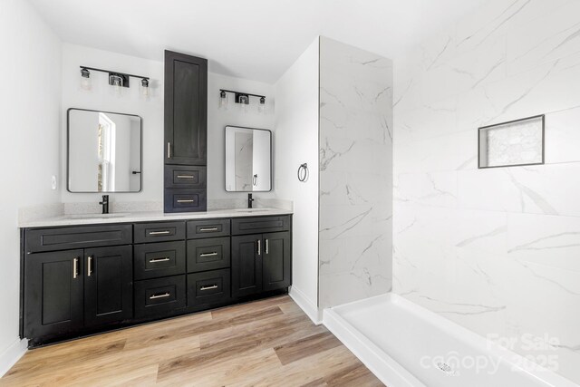 full bath featuring double vanity, wood finished floors, and baseboards