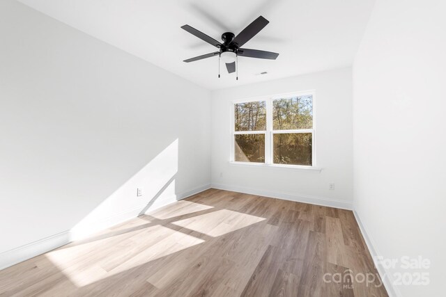spare room with baseboards, light wood-style flooring, and ceiling fan