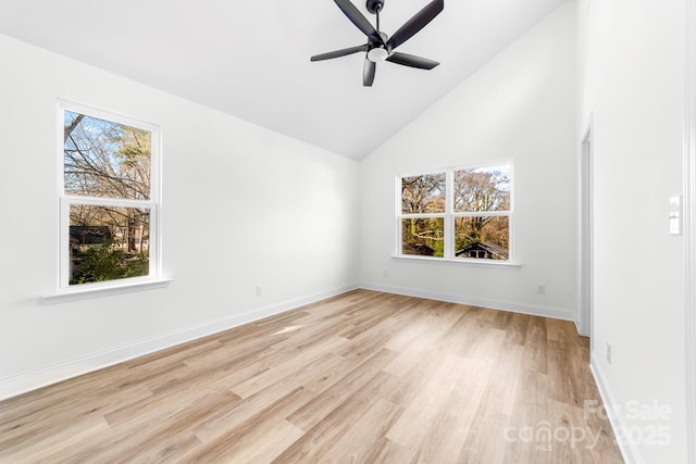 empty room with light wood finished floors, high vaulted ceiling, ceiling fan, and baseboards