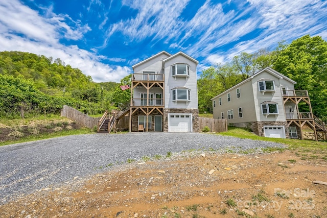 274 Old Bristol Rd, Boone, NC 28607 - coastal inspired home with stairway, a balcony, stone siding, an attached garage, and gravel driveway