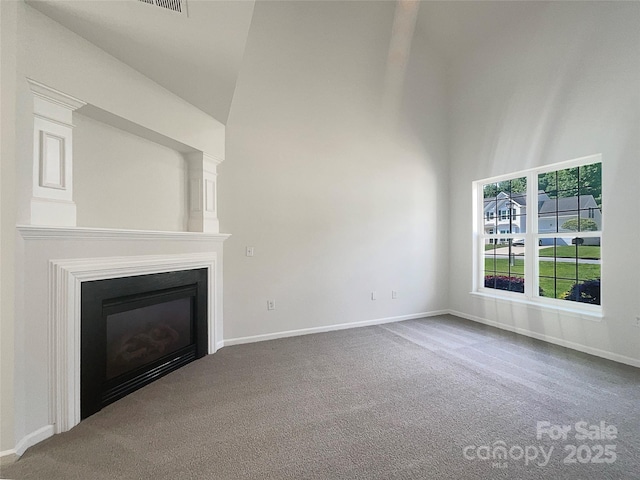 unfurnished living room featuring a high ceiling, a glass covered fireplace, and carpet floors