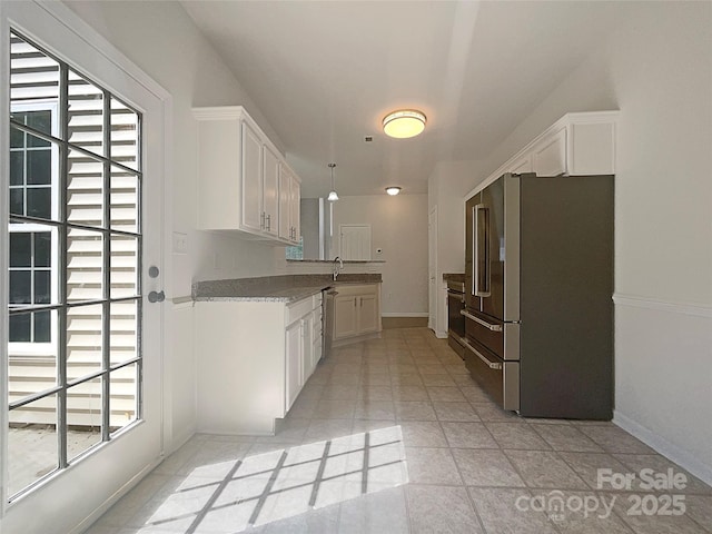 kitchen featuring freestanding refrigerator, a wealth of natural light, and white cabinetry
