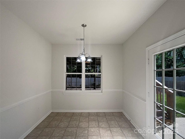 empty room featuring stone finish flooring, a notable chandelier, baseboards, and visible vents