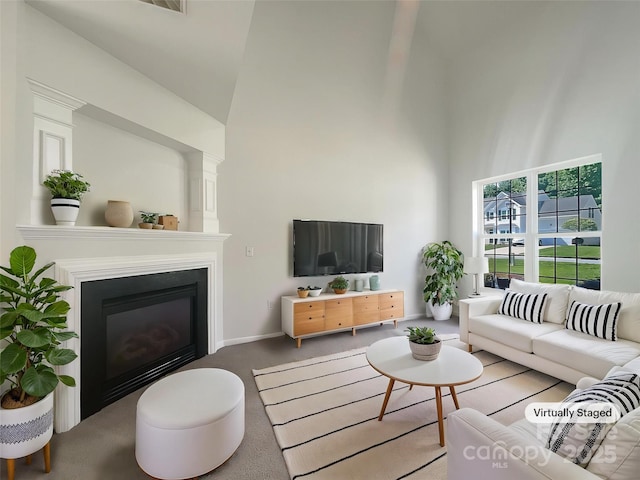 carpeted living room with a high ceiling and a glass covered fireplace