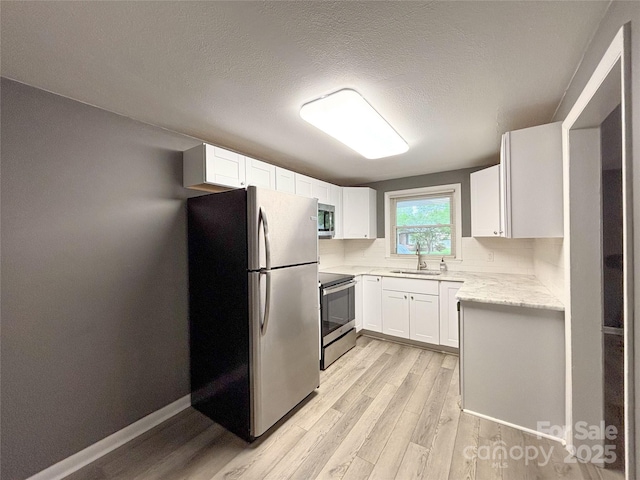 1464 19th Ave NE, Hickory, NC 28601 - kitchen with stainless steel appliances, a sink, light wood-style flooring, white cabinets, and light stone countertops