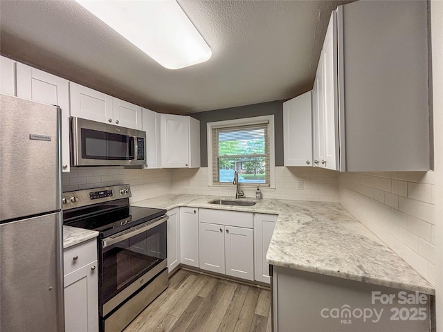 1464 19th Ave NE, Hickory, NC 28601 - kitchen featuring stainless steel appliances, a sink, light wood-style flooring, decorative backsplash, and a textured ceiling