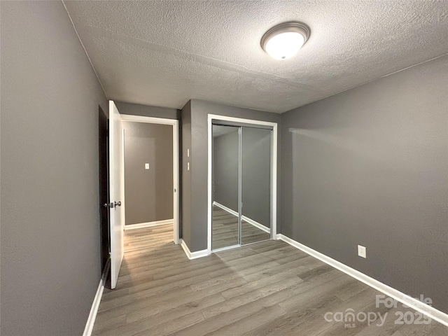 1464 19th Ave NE, Hickory, NC 28601 - unfurnished bedroom with a textured ceiling, wood finished floors, a closet, and baseboards
