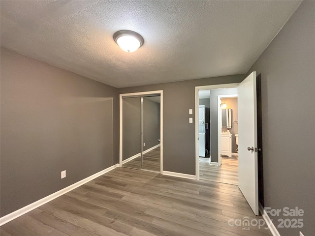 1464 19th Ave NE, Hickory, NC 28601 - unfurnished bedroom featuring a textured ceiling, wood finished floors, baseboards, a closet, and refrigerator
