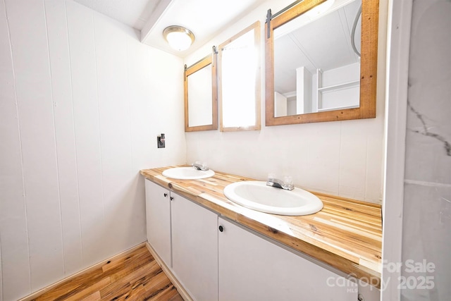 bathroom with double vanity, a sink, and wood finished floors