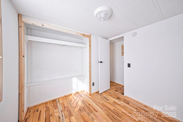 unfurnished bedroom with a textured ceiling, a closet, and wood finished floors