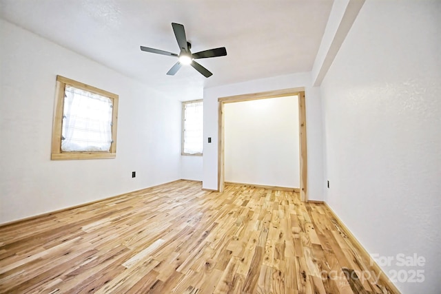 empty room with plenty of natural light, light wood-style flooring, and ceiling fan