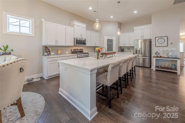 kitchen featuring stainless steel appliances, a sink, a kitchen bar, white cabinets, and recessed lighting