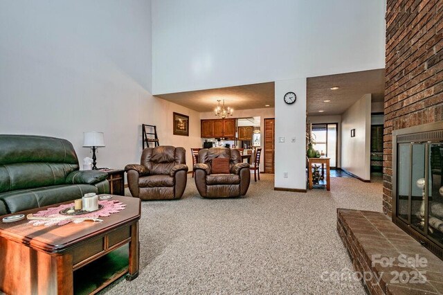 living room with a towering ceiling, a chandelier, light colored carpet, and a fireplace