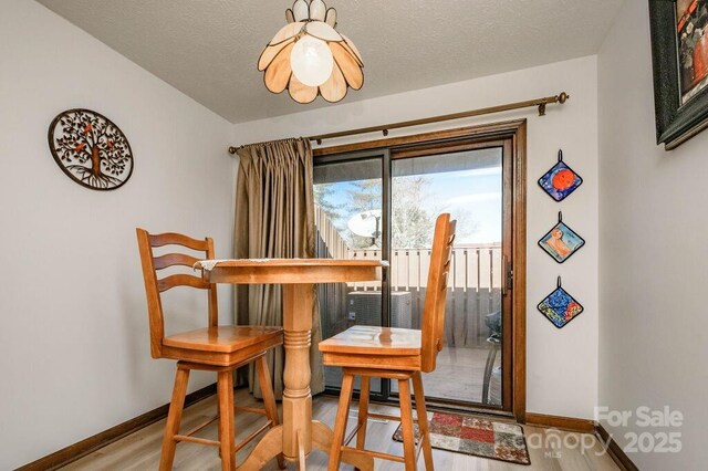 dining area with baseboards, wood finished floors, and a textured ceiling