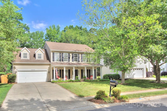 view of front of home featuring driveway, a porch, a front yard, an attached garage, and a shingled roof