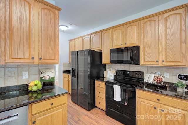 kitchen featuring black appliances, light brown cabinetry, decorative backsplash, and dark stone counters