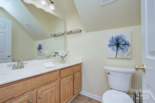 bathroom featuring toilet, vaulted ceiling, vanity, tile patterned floors, and baseboards