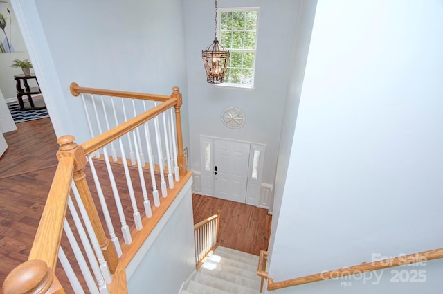 stairway featuring a chandelier, wood finished floors, and a high ceiling