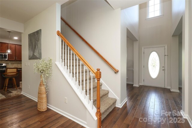 10217 Falling Leaf Dr, Concord, NC 28027 - entryway featuring dark wood-style flooring, stairway, baseboards, and a towering ceiling