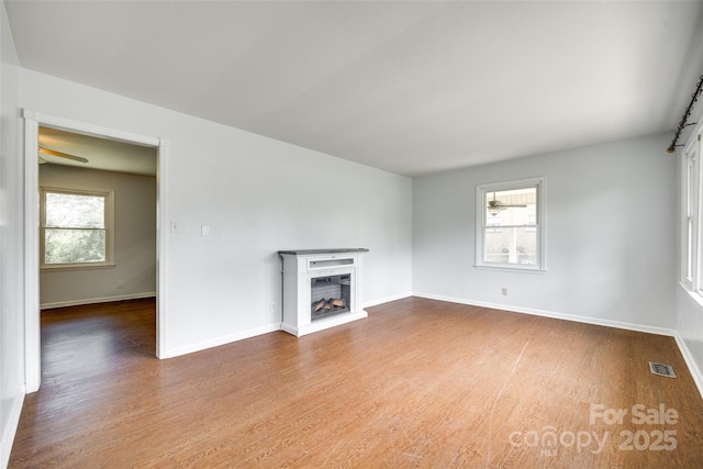 unfurnished living room featuring wood finished floors, baseboards, and a fireplace