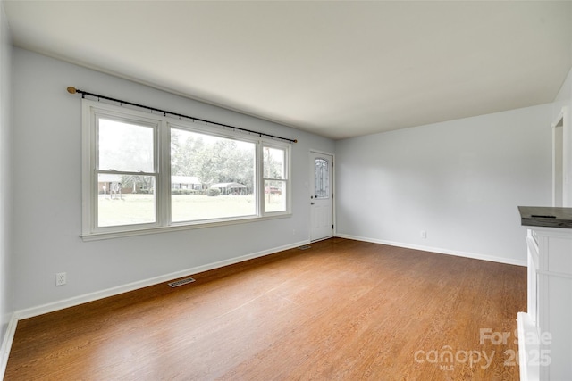 unfurnished living room with wood finished floors and baseboards