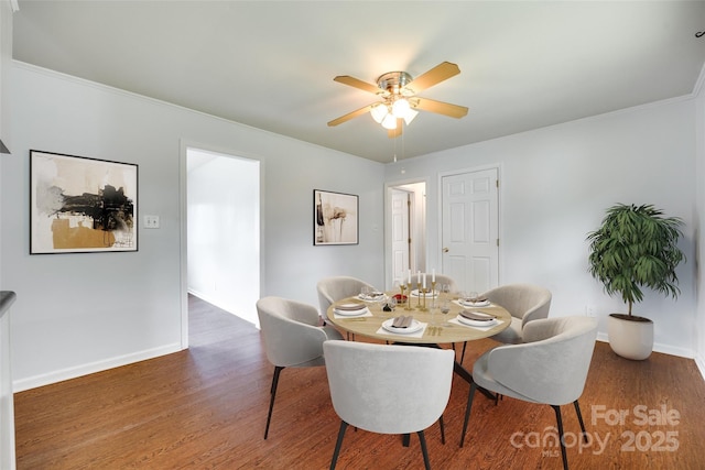 dining room with a ceiling fan, wood finished floors, baseboards, and ornamental molding