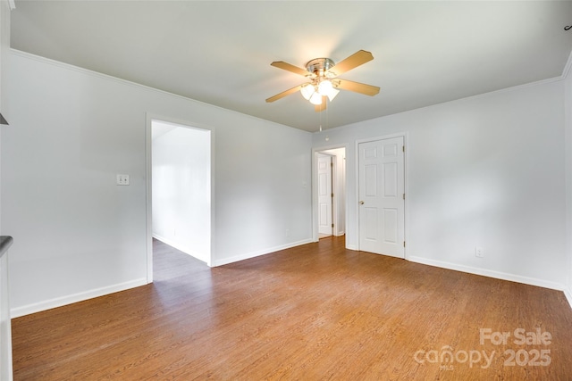 unfurnished room featuring wood finished floors, ceiling fan, baseboards, and crown molding
