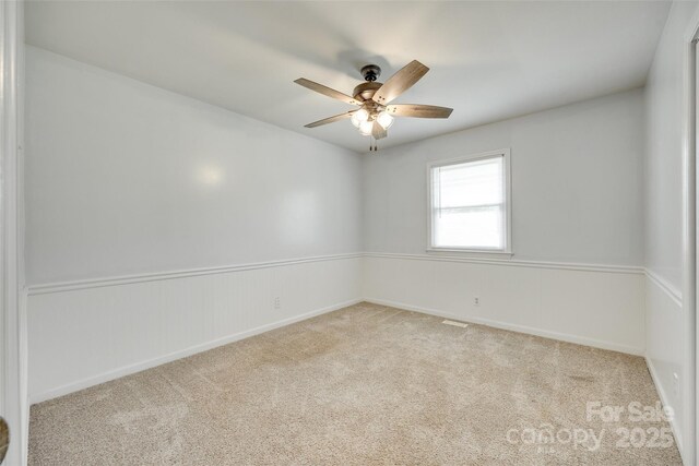 empty room featuring carpet flooring, a ceiling fan, and baseboards