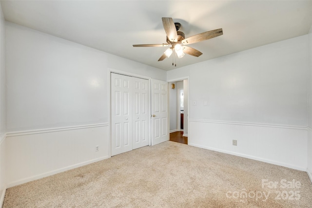 unfurnished bedroom featuring carpet flooring, a closet, a ceiling fan, and baseboards