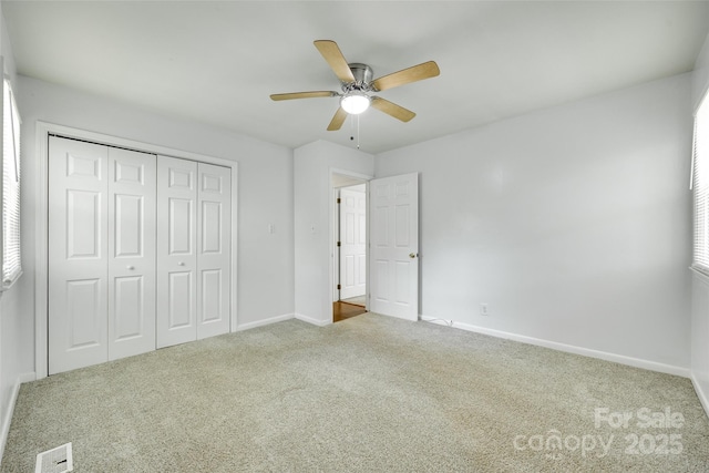 unfurnished bedroom featuring carpet floors, baseboards, a closet, and a ceiling fan