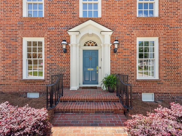 entrance to property featuring crawl space and brick siding