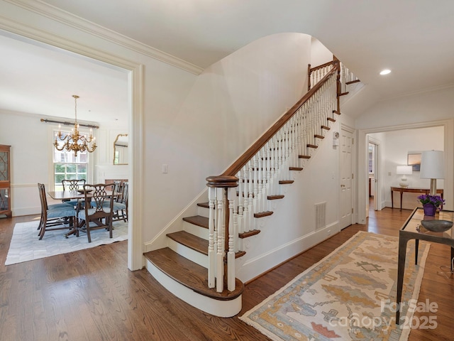 stairway featuring wood finished floors, baseboards, a chandelier, crown molding, and recessed lighting