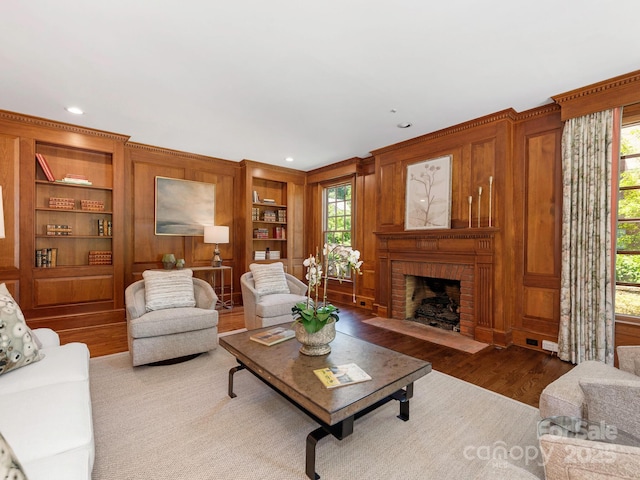 living area with a fireplace, built in features, wood finished floors, and recessed lighting