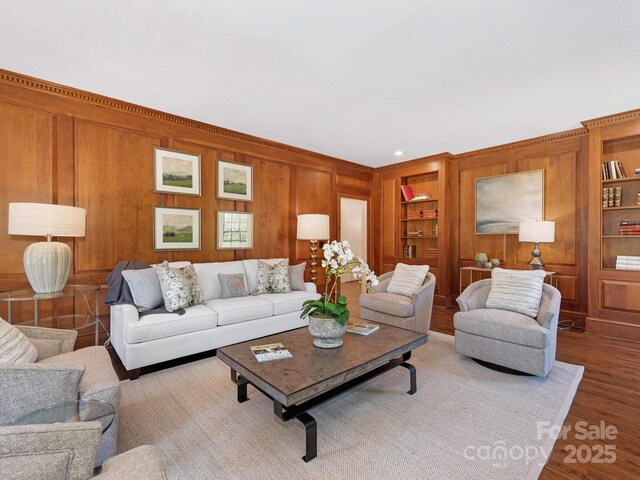 living room featuring wood finished floors, built in shelves, and wooden walls