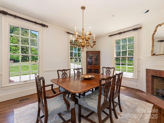 dining area with a chandelier, light wood-style floors, crown molding, a fireplace, and baseboards