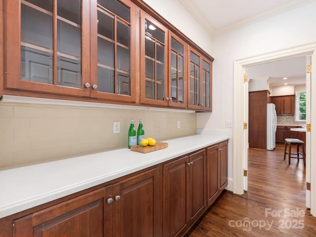 bar with freestanding refrigerator, backsplash, dark wood-style floors, and ornamental molding