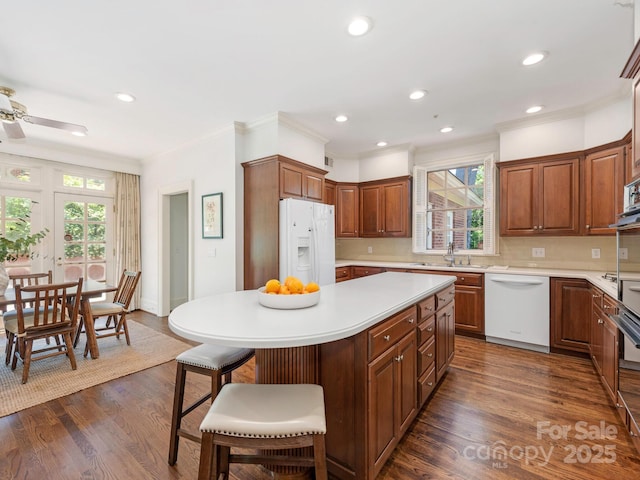 kitchen with white appliances, light countertops, crown molding, plenty of natural light, and a sink