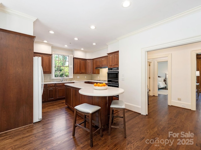 kitchen featuring white appliances, crown molding, light countertops, a kitchen island, and a breakfast bar