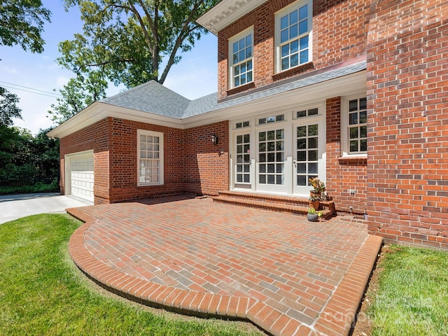 view of patio / terrace featuring an attached garage, driveway, and french doors