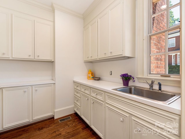 kitchen featuring a sink, crown molding, light countertops, dark wood-type flooring, and white cabinetry