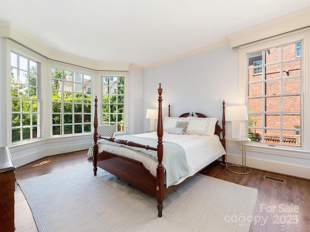 bedroom with wood finished floors, multiple windows, baseboards, and ornamental molding