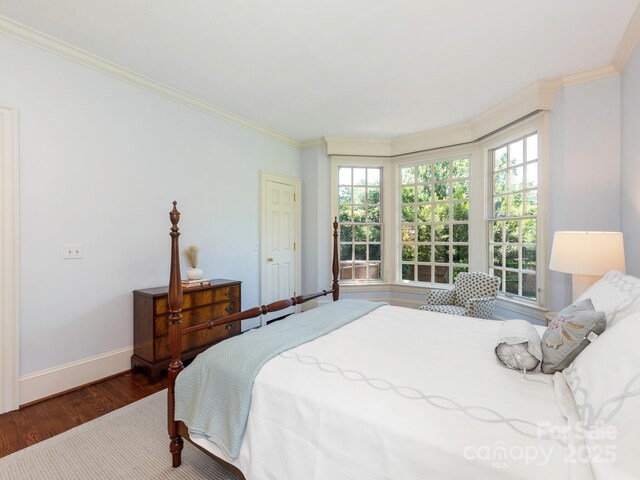 bedroom with wood finished floors, baseboards, and ornamental molding