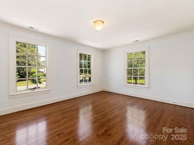 spare room with healthy amount of natural light, crown molding, baseboards, and dark wood-style floors