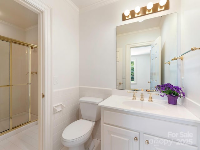 full bathroom featuring a stall shower, vanity, tile walls, toilet, and ornamental molding