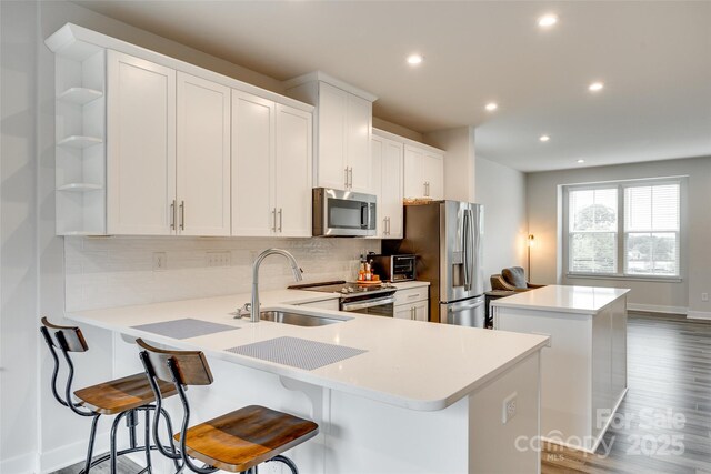 kitchen featuring stainless steel appliances, a sink, a center island, backsplash, and recessed lighting