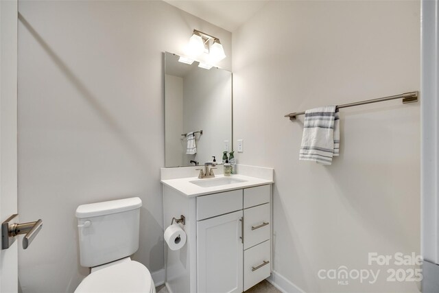 half bathroom with toilet, vanity, and baseboards