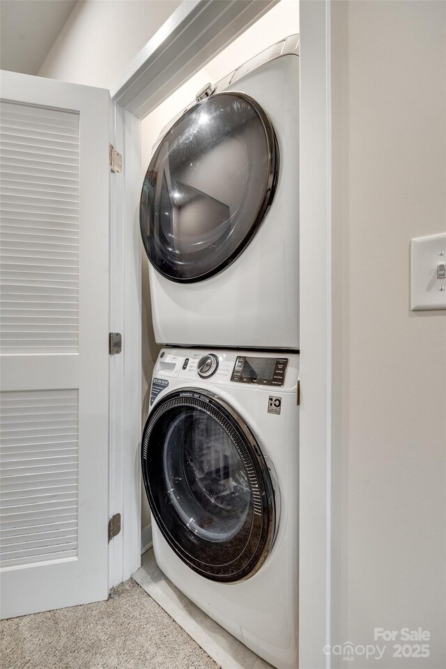 laundry room featuring stacked washing machine and dryer and carpet floors