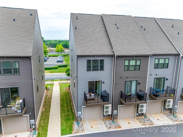 back of property featuring a garage, ac unit, and roof with shingles